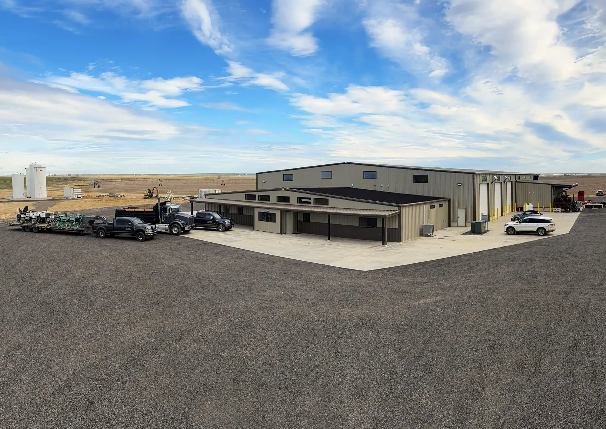 Completed EXCO steel building complex with concrete apron and jobsite vehicles